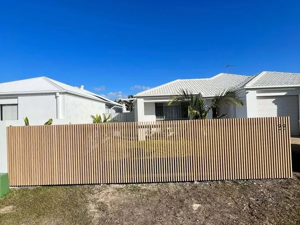 Woodgrain aluminium batten fence in front of single-storey rendered homes