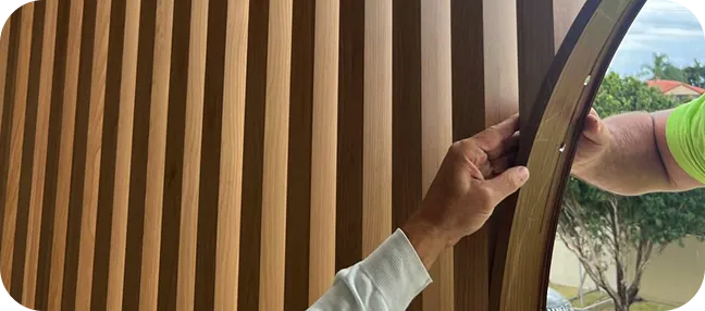 Installer fitting a curved frame section to a woodgrain aluminium batten screen