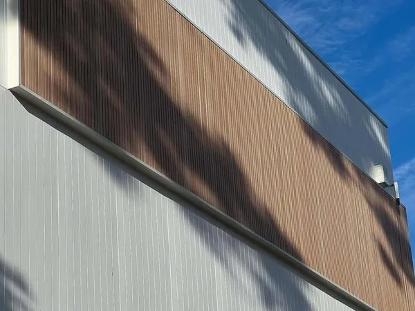Wide band of woodgrain aluminium battens across a white-clad upper storey