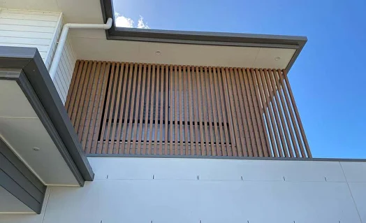 Woodgrain aluminium battens screening an upper window beneath the eaves