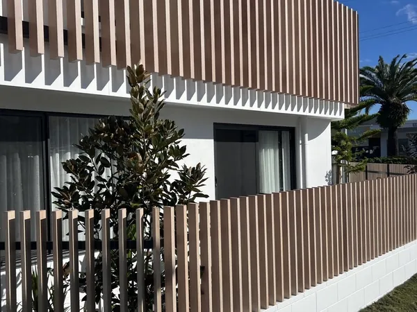 Woodgrain aluminium batten fencing on a white masonry base